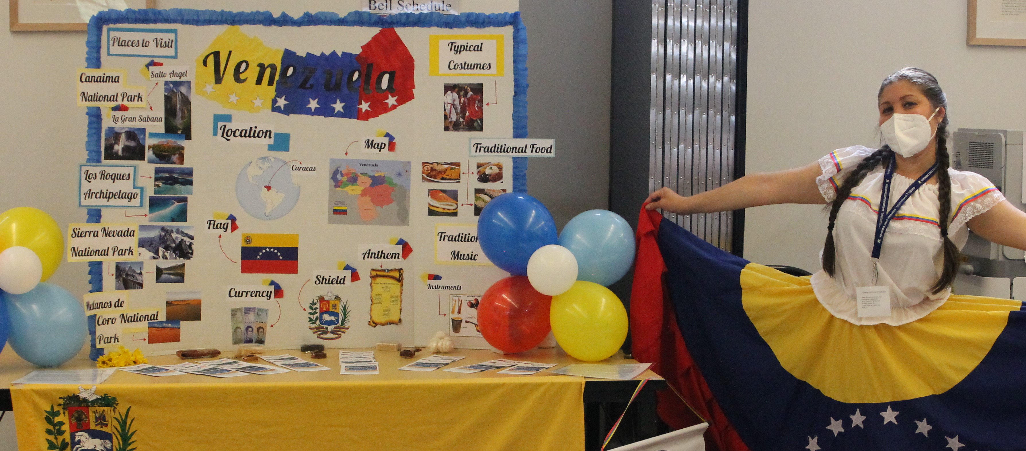 A young woman in Venezuelan colors (red, blue, yellow) poses in front of a poster about her home century.