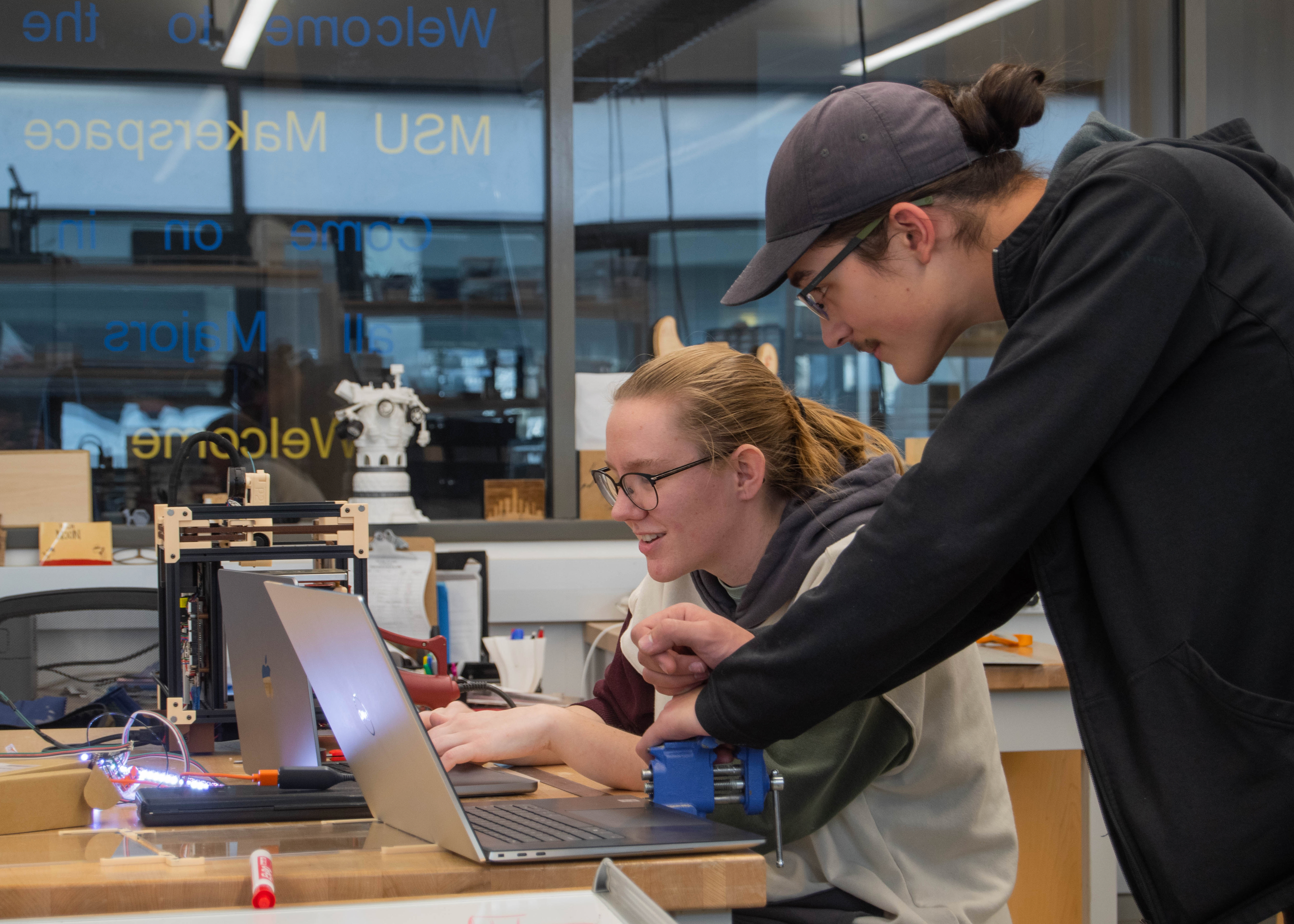 Students work together to flush out coding on a homemade 3D printer