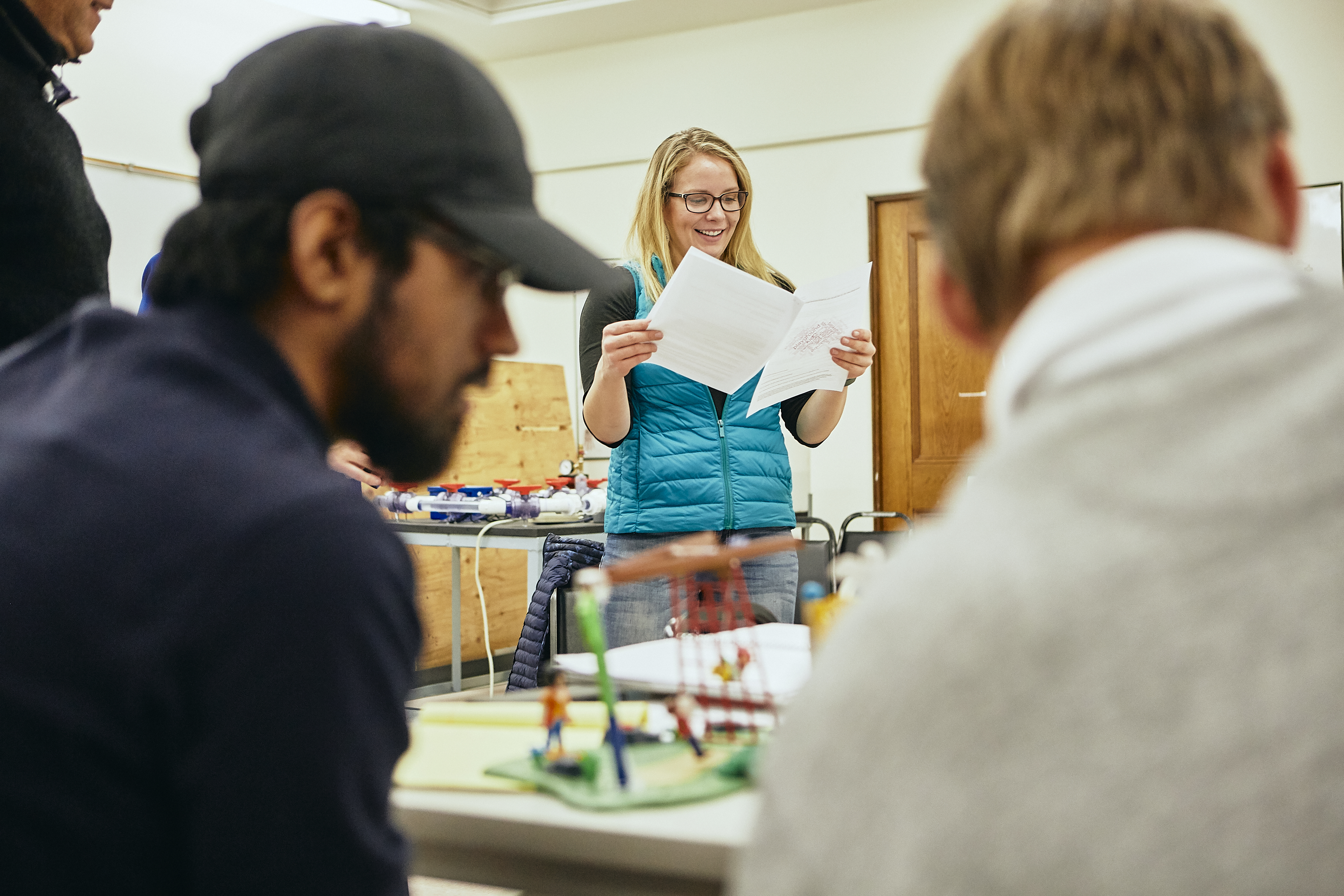 a student wearing a teal shirt gestures while talking with her faculty member