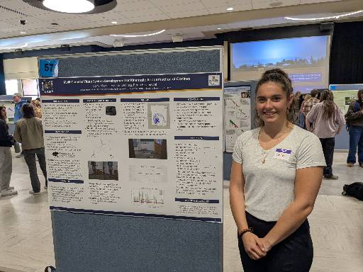 Student standing next to research poster