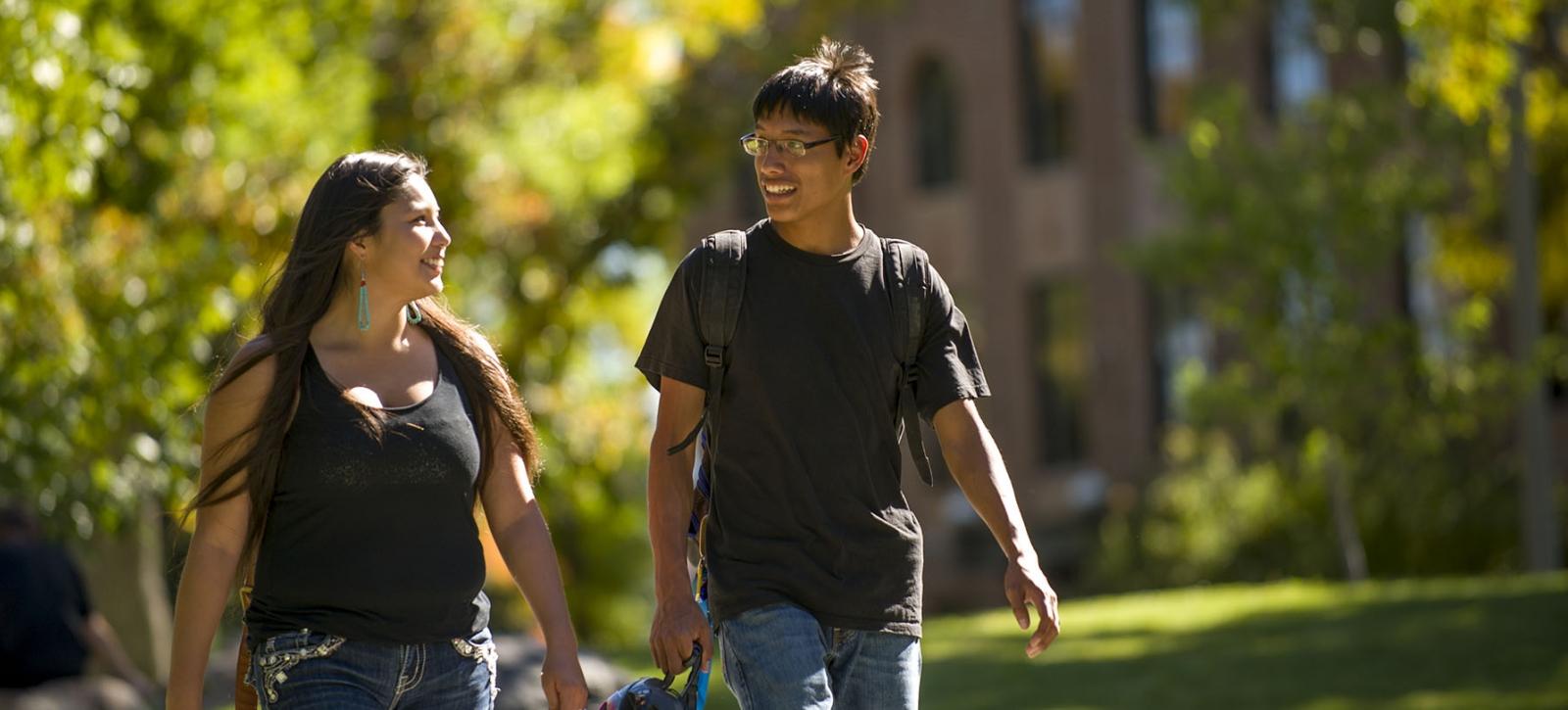 two native american students walking through campus in the afternoon