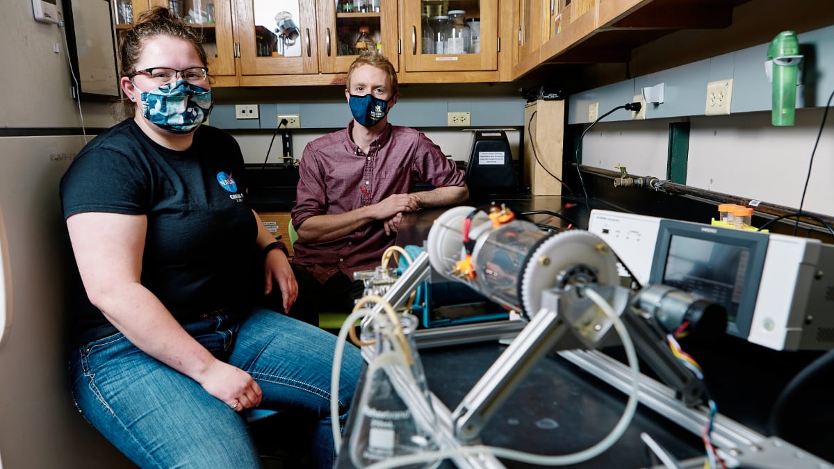 Two students pose in a laboratory at a workbench.