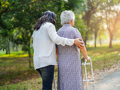 elderly adult walking with walker and a friend
