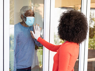 senior looking at family member through glass senior looking at family member through glass
