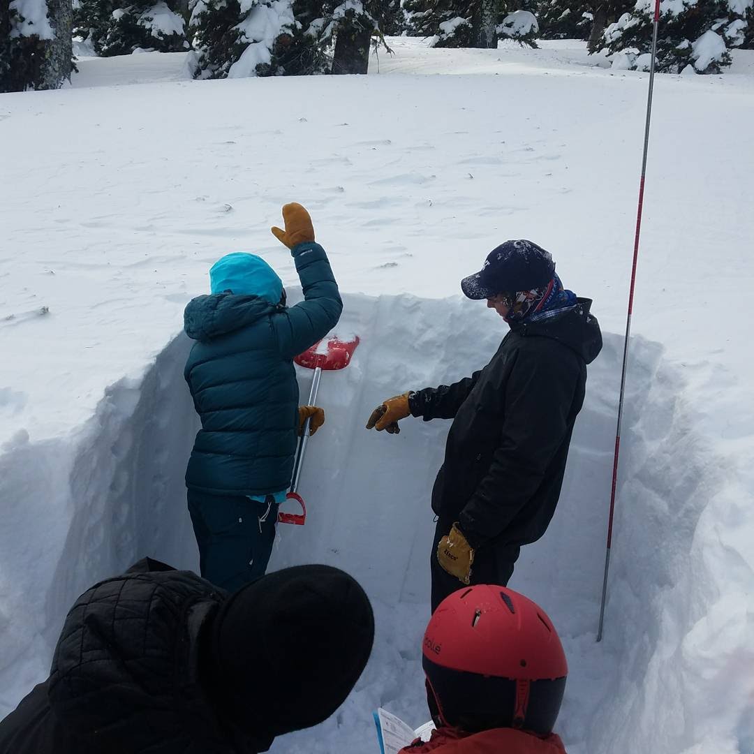 instructor working with student in avalanche education course
