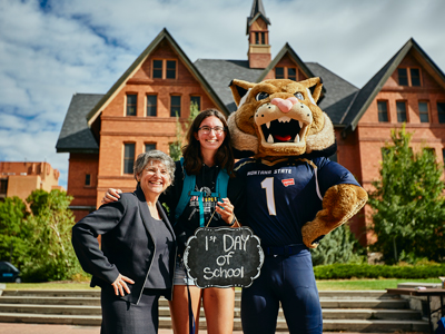 Photo of a freshman student posing with Champ and President Cruzado