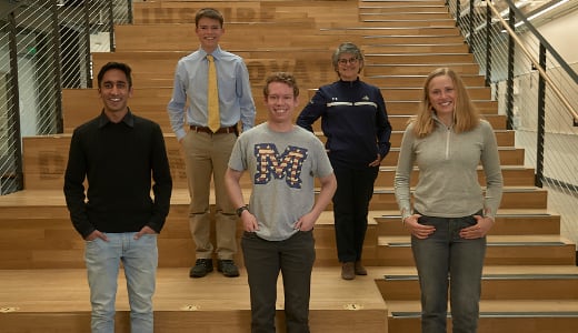 Five people pose on a set of stairs.