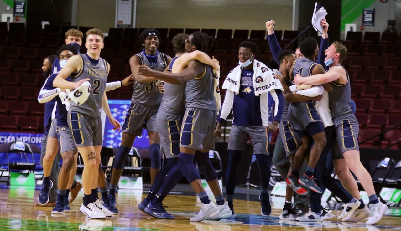 Members of a men's basketball team celebrate on a basketball court.