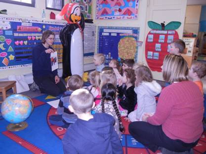 preschool students sitting on rug watching teacher