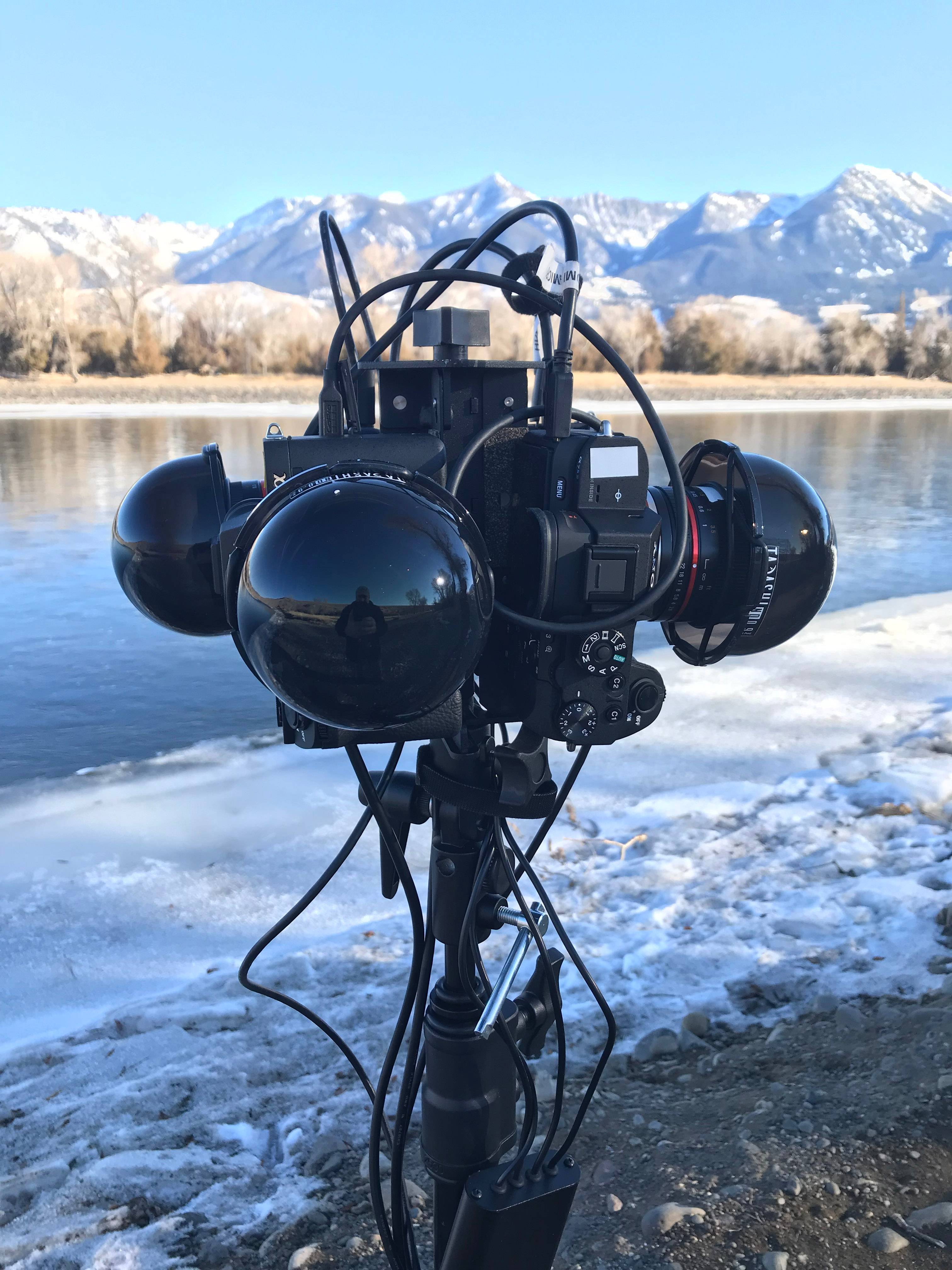 360-degree camera rig by a river with mountains in the background