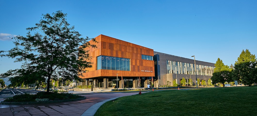 Scenic shot of Norm Asbjornson Hall during summer with honeylocust tree in foreground.