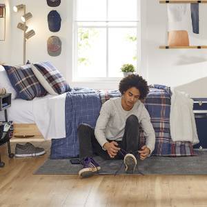 Young man tying shoe with linens on bed