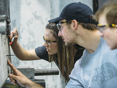 Students in safety goggles examine a concrete block
