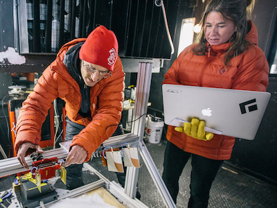 two MSU students in orange coats working in cold room