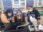 Two masked students working on a computer connected to a microscope. 