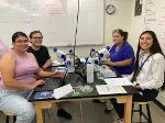 Four students pause working to smile at the camera, they are a group assigned to work together. 