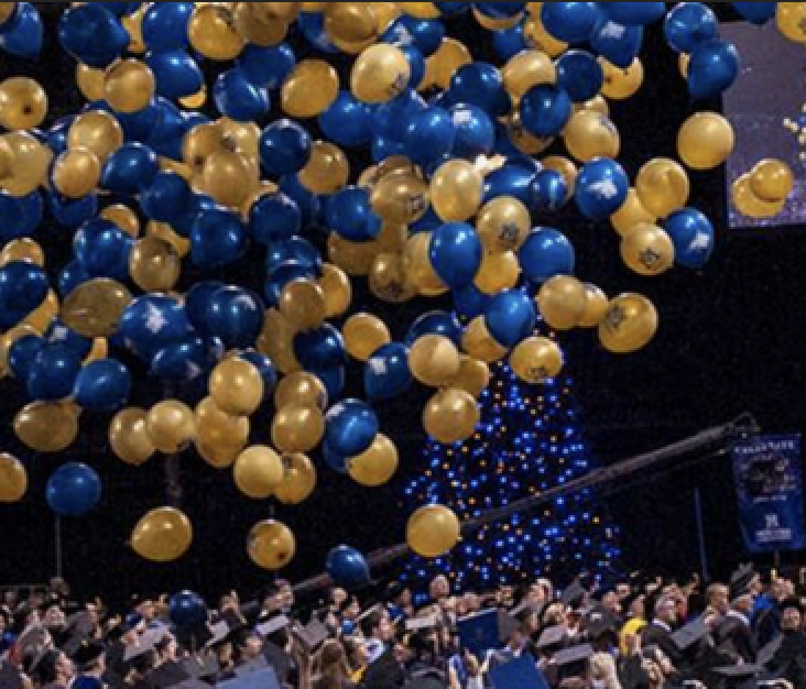 Blue and gold balloons falling on Montana State University graduates in the field house