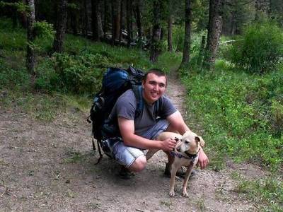 Levi kneeling next to his dog in the woods