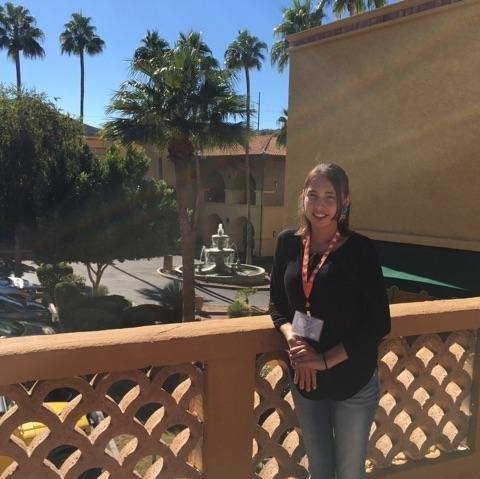 Reisa Walker on a balcony with sunlight and palm trees in the back